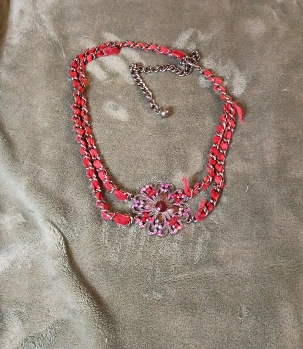 Multi Strand Necklace Featuring Interwoven Ribbon Centered Around Ornate Floral